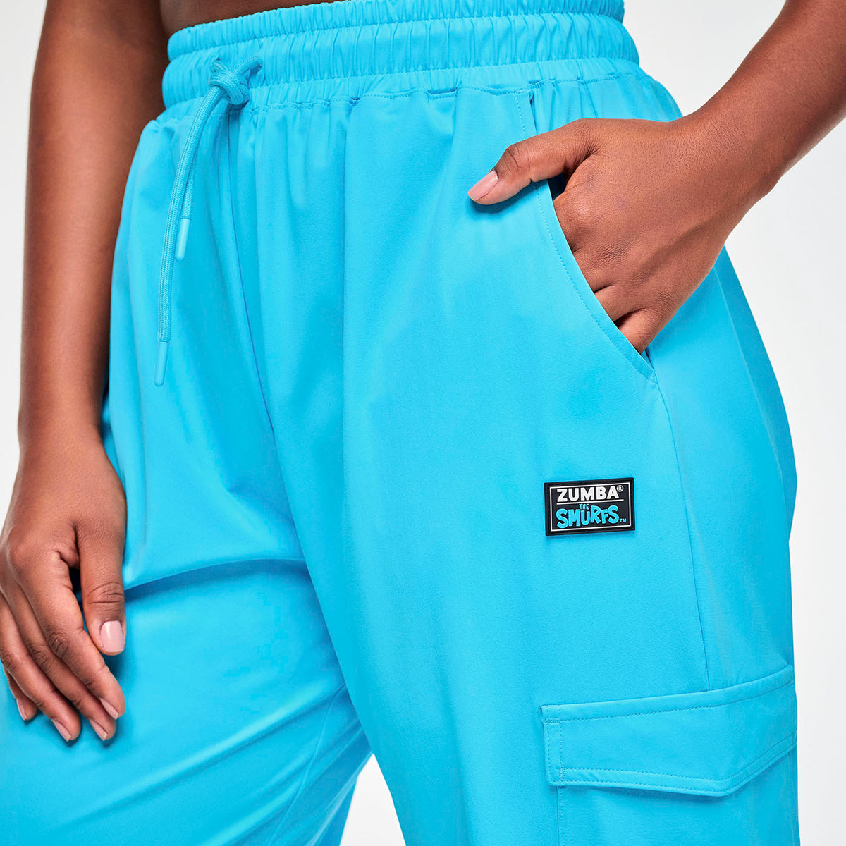Turkusowe spodnie cargo baggy – detal kieszeni i naszywki ZUMBA x SMURFS | Zumba Wear