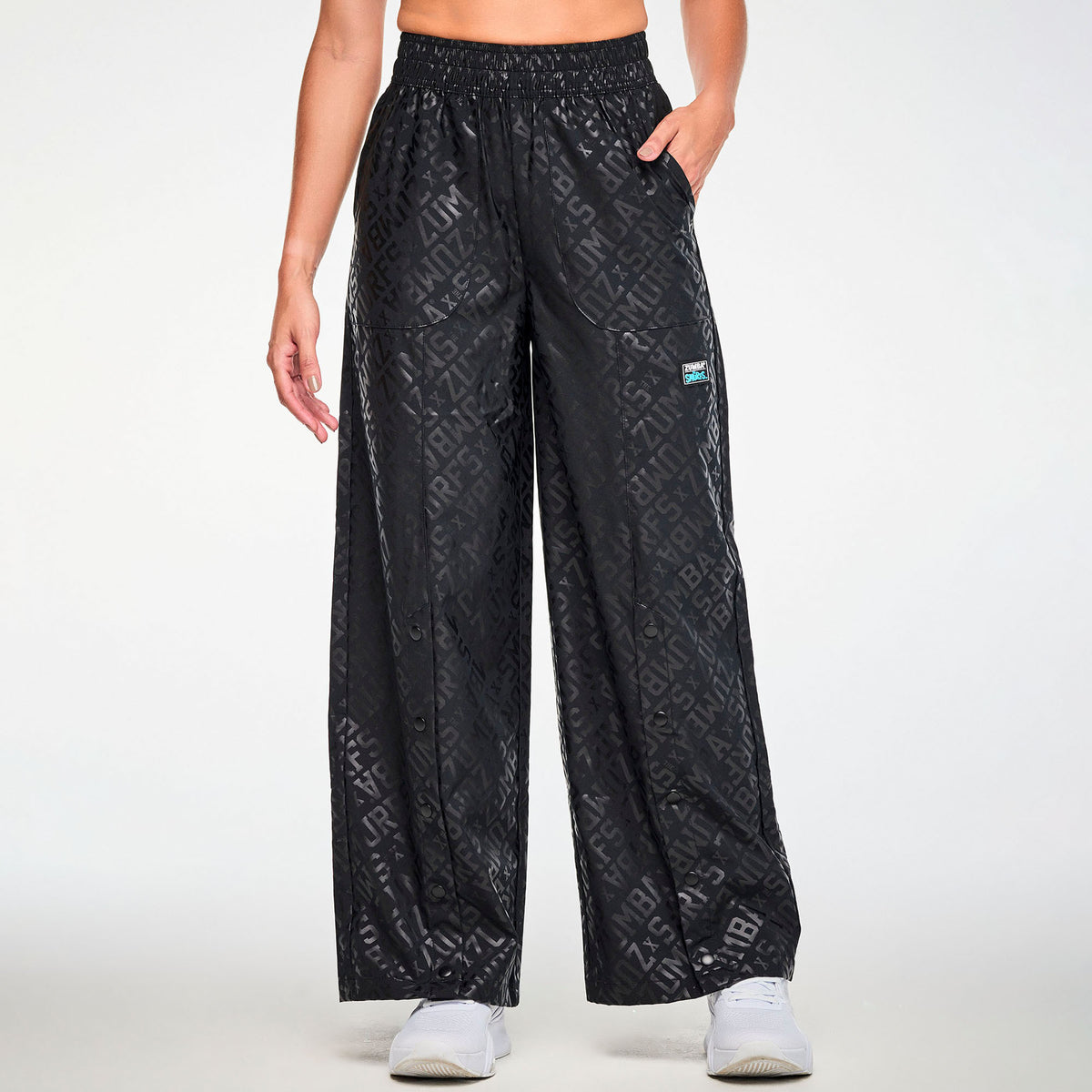 Czarne spodnie z szerokimi nogawkami i zatrzaskami – widok z przodu na modelce | Zumba Wear