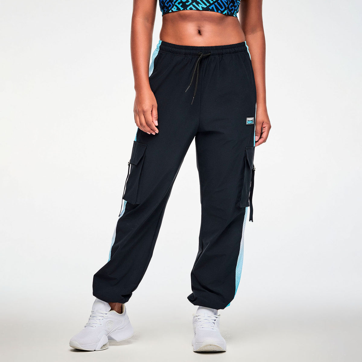 Czarne spodnie cargo unisex z siateczkowymi lampasami – widok z przodu na modelce | Zumba Wear